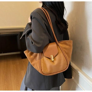 Detailed view of brown suede bucket tote bag with gold buckle on a model