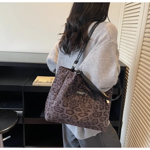 Detail of leopard print tote bag with leather straps and decorative fashion label tag