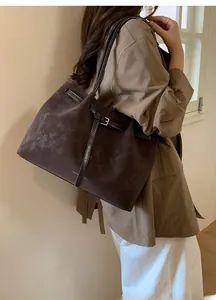 Macro detail of large dark brown suede tote bag with metallic buckle and shoulder strap