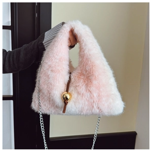 Détail du sac à main en fausse fourrure rose avec boule dorée et bandoulière chaîne