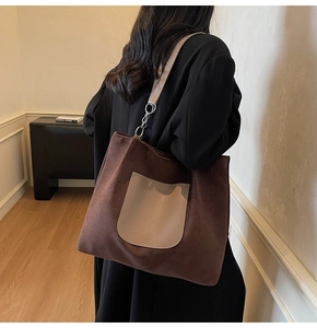 Detail of dark brown tote bag featuring contrast pocket and silver chain strap