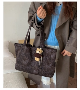 Close-up of large leopard print tote bag with brown bear charm on khaki coat