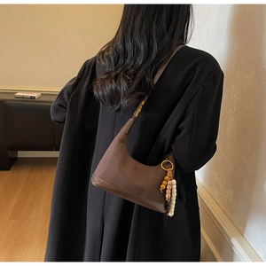 Détail du sac hobo en daim marron foncé avec pendentif en perles et bandoulière
