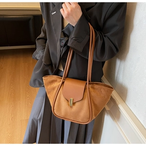 Detail of a brown suede bucket bag featuring a gold metal buckle and smooth leather trim