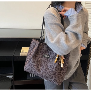Detail of leopard print tote bag with wood bead charm and black faux leather straps