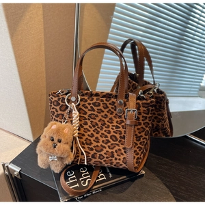 Dettaglio borsa a secchiello leopardata con tracolla in pelle marrone e ciondolo a cane
