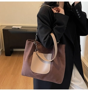 Detail of large brown suede tote bag with chain strap and beige leather pocket