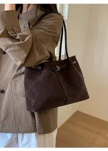Close-up of a large dark brown suede tote bag styled with an autumn trench coat