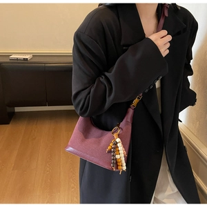 Détail du sac hobo bordeaux avec texture mate et perles en bois porté par un mannequin
