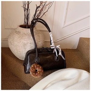 Détail d'un sac Boston vintage marron avec un nœud à carreaux et un charme donut