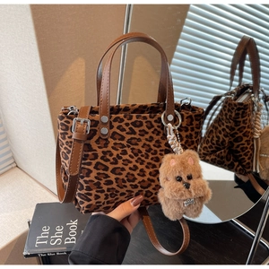 Dettaglio borsa tote leopardata con manici in pelle marrone e ciondolo a cane peluche