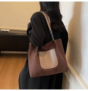 Detail of brown suede tote bag with beige saddle pocket and metal chain strap