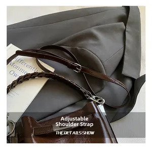 Detail of dark brown patent leather bucket bag with adjustable strap and woven handle