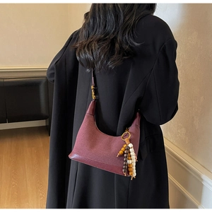 Détail du sac dumpling en daim bordeaux avec perles ethniques et finitions en cuir