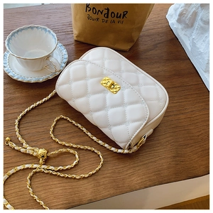 Close-up of white quilted crossbody bag with gold chain strap and adjustable gold ball