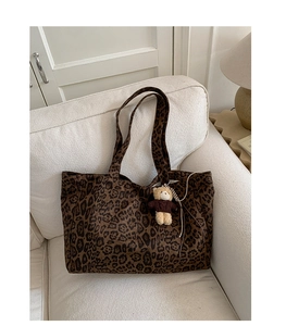 Detailed close-up of a large leopard print tote bag with a cute bear plush keychain