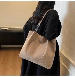Detail of khaki tote bag with BUDBAO logo pocket and metal chain shoulder strap