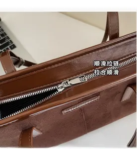 Close-up of smooth silver metal zipper and brown suede stitching on the leather tote bag