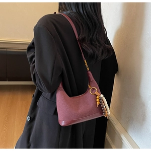 Détail du sac hobo bordeaux au fini mat avec pompon en perles de bois élégant