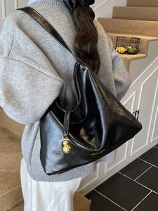Sac hobo vintage minimaliste en cuir verni noir avec un pendentif en boule dorée