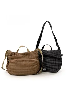 Gros plan de sacs bandoulière imperméables à carreaux marron et noir avec détail de zip