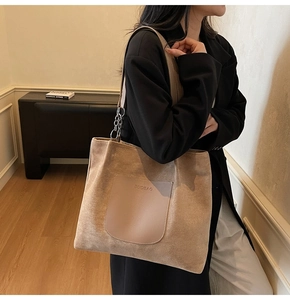 Detail of light brown tote bag featuring suede texture and leather strap with chain