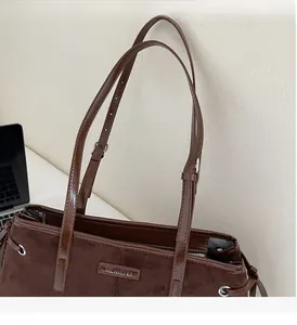 Detail of dark brown faux suede tote bag with adjustable strap and metallic logo