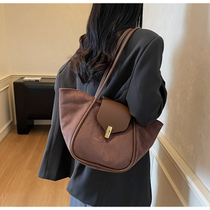 Detail of dark brown suede tote bag with metal buckle shown on model's shoulder