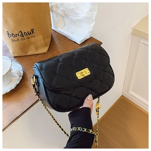 Detail of black quilted crossbody bag with golden chain strap and metallic twist lock