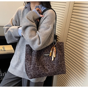 Detailed shot of large leopard print tote bag with beaded charm on shoulder of model