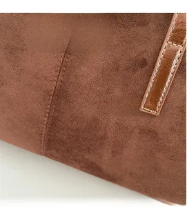 Macro detail of vintage brown suede tote bag featuring fine stitching and brand logo tag