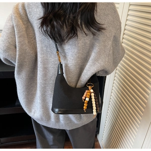 Détail du sac dumpling noir en toile avec perles en bois colorées sur l'épaule