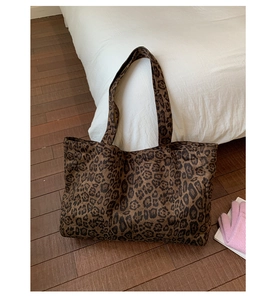 Macro detail of large leopard print canvas tote bag on floor showing texture and spacious size