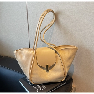 Detail of light khaki bucket bag with suede texture and gold buckle on art books