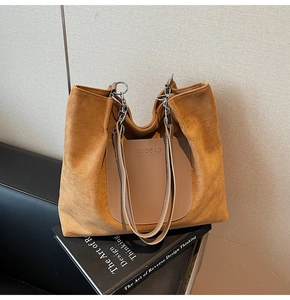 Detail of suede tote bag showing front pocket and metal chain leather shoulder strap