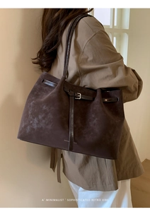 Detail shot of dark brown suede tote with sleek leather straps and buckle decor