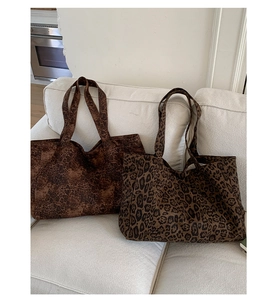 Detailed view of two leopard print tote bags in soft velvet material on a cozy sofa