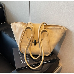 Detail of beige tote bag showing suede and smooth leather texture with gold buckle lock