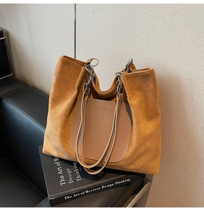 Detailed close-up of brown suede tote bag with leather pocket and metal chain strap