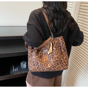 Detailed shot of leopard print tote bag featuring brown leather strap and wooden beads