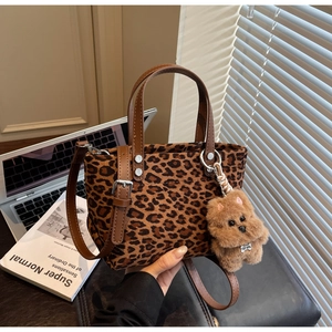 Dettaglio della borsa leopardata con manico in pelle marrone e ciondolo a forma di cane