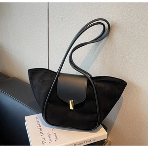 Detail of black suede and smooth leather bucket bag featuring a gold rectangular buckle