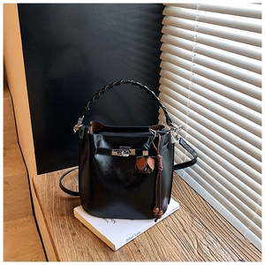 Detail of black leather bucket bag with woven handle, silver twist lock and tassel charm