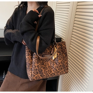 Detail of leopard print tote bag featuring brown leather straps and beaded pendant charm