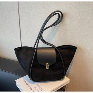 Detail of black suede bucket bag featuring golden metal lock and leather stitching texture