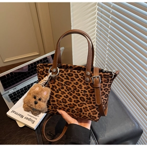 Dettaglio della borsa tote leopardata con manici marroni e ciondolo a forma di cucciolo