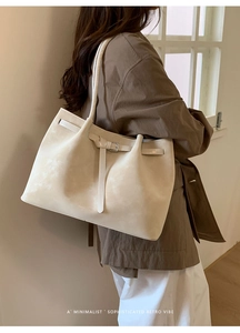 Detail view of beige matte leather tote bag with metallic buckle and shoulder strap