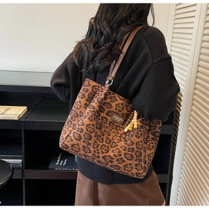 Detail of leopard print tote bag featuring brown leather straps and wooden bead charm