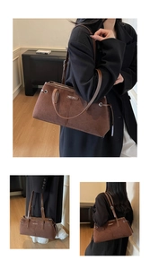 Detail of vintage brown suede tote bag with metallic logo and textured shoulder strap