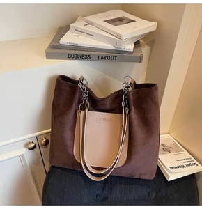 Close-up of brown suede tote bag with khaki leather pocket and metal chain handle